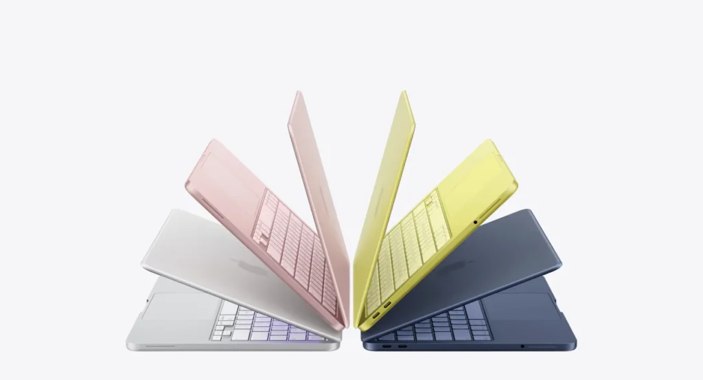 MacBook Neo laptops in silver, blush, citrus, and indigo colors, slightly open and arranged in an arch formation